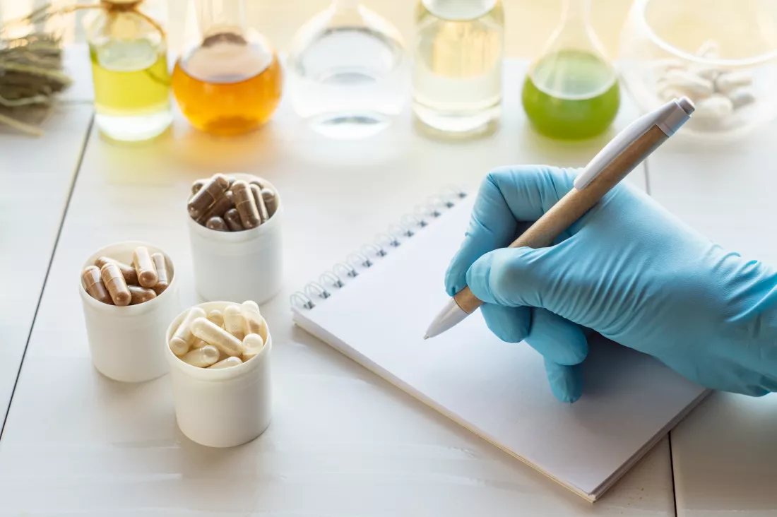 dietary-supplement-capsules-ingredients-hand-pharmacist-writes-notebook