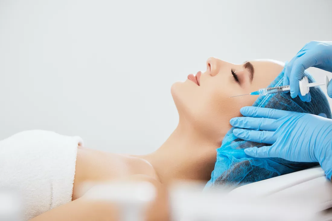 profile-woman-blue-cap-lying-couch-cosmetological-clinic-doctor-s-hands-blue-gloves-doing-contouring-plastic-surgery-with-syringe-with-filler-closeup