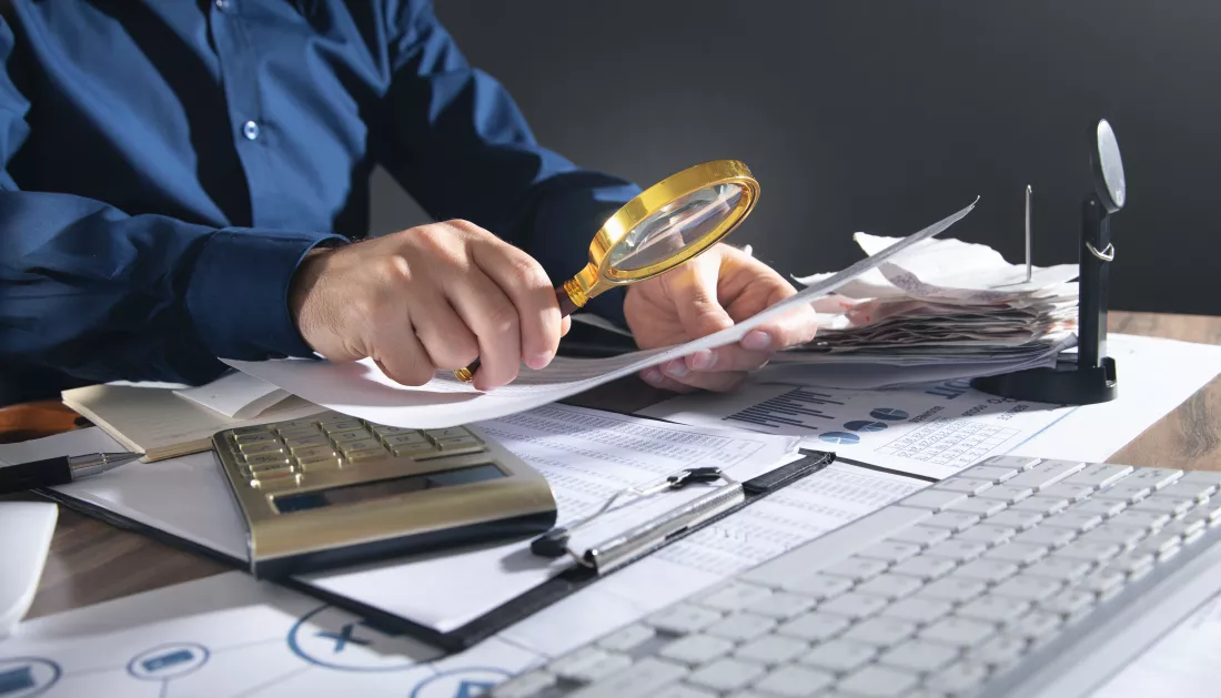 businessman-holding-magnifying-glass-with-documents